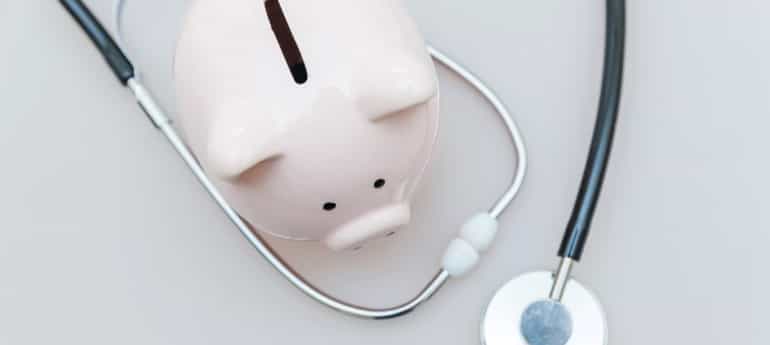 a stethescope around a piggy bank on a table